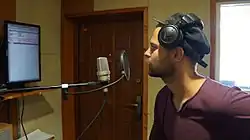 Personne de profil portant un casque et utilisant un microphone.