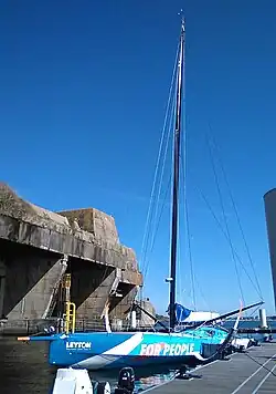 Vu de trois quarts avant, en entier, bateau bleu sombre et bleu clair amarré au ponton.