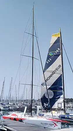 Voilier blanc et rouge vu de trois quarts avant, amarré au ponton.