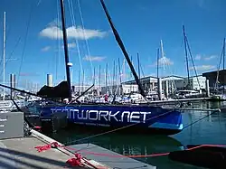 Vu de trois quarts avant, bateau bleu amarré au ponton.