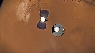 Vue d'artiste montrant vue du dessus avec la surface de Mars en arrière plan les deux modules d'InSight peu après leur séparation.