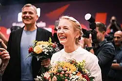 Ines Schwerdtner tient un bouquet de fleurs et rit.
