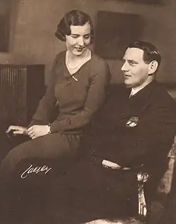 Photographie en noir et blanc d'un homme et d'une femme assis côte à côte ; la femme regarde l'homme.