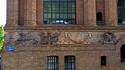 Photographie des sculptures ornant le mur d'un bâtiment, et parmi elles un aigle aux ailes étendues.
