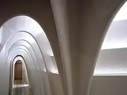 Enfilade d'arcs caténaires de couleur blanche dans un couloir étroit. Mise en avant de la lumière.