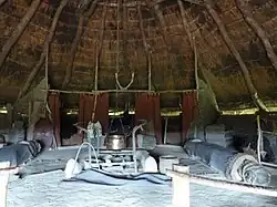 Photo de l'intérieur d'un bâtiment rond avec un foyer ouvert au milieu et des tentures écarlates sur les murs