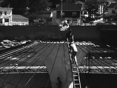 Jocelyn Maltais procédant à l'action performative Intervention 58 sur la fontaine du centenaire d'Alma devenue inopérante à cause de la pollution de la rivière.