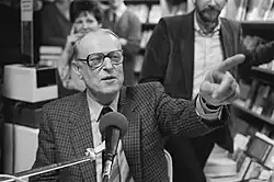 photographie en noir et blanc d'un homme de face pointant son index gauche en direction du photographe