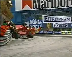 Photo d'une monoplace rouge en position verticale, en train de s'écraser contre un rail de sécurité