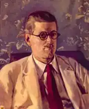Half-length portait of a fortyish man wearing distinctive Windsor (circular-lens) glasses with black Zylo-covered frames, short and slicked-down brown hair, a small mustache, light tan jacket, and brown tie. His mouth is turned down in a slightly truculent expression