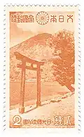 Timbre bicolore orange et blanc montrant une montagne au bord d'un lac, avec au premier plan, un portail traditionnel de sanctuaire shinto.