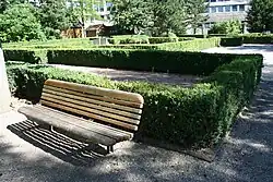 Vue générale du jardin avec un banc et à l'arrière-plan les haies végétales de localisation des murs des thermes