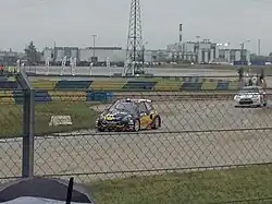 Sur une piste humide, une voiture noire roule.