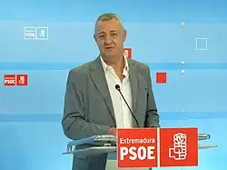 Un homme debout derrière un pupitre prononçant un discours.