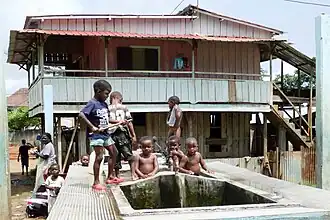 Maison sur pilotis et fontaine.