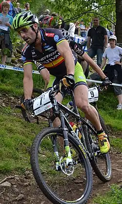  Homme descendant une pente à VTT dans une tenue noire et verte.