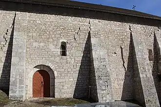 Façade ouest soutenue par d'imposants contreforts.