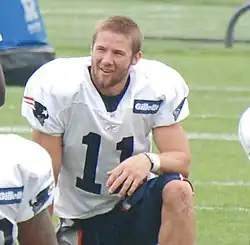 Un joueur de football américain en tenue sans casque, agenouillé au sol.