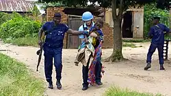 Un militaire et un policier transportent une femme blessée.