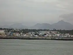 Vue sur le port de Kanyakumari et son quartier de pêcheurs. À l'horizon peuvent être distingués les premiers massifs des Ghats occidentaux (tels que le Velimalai, le Thekkumalai, l'Asambu, etc.).