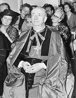 Photographie en noir et blanc du Cardinal Ottaviani assis avec un groupe de fidèles lors d'un évènement.