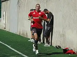 Photo de Karim Benzema effectuant un footing sur le bord de la pelouse avec le maillot de l'Olympique lyonnais.