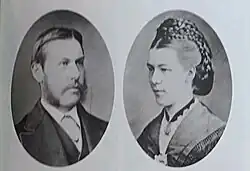 Double médaillon en vis à vis. À gauche : un homme en costume avec une barbe à l'anglaise sans poil au menton. A droite : une femme avec une coiffure relevée élaborée.