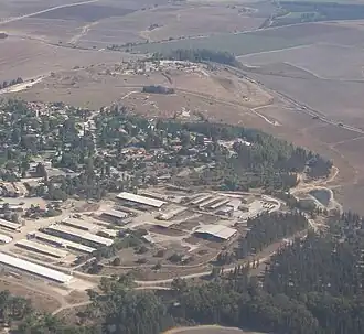 Vue aérienne de bâtiments sur une hauteur, au milieu des champs.