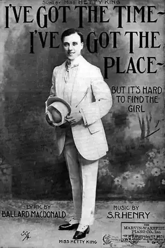 Affiche en noir et blanc d'un male impersonator blanc portant un costume trois pièces et s'inclinant en tenant son chapeau dans la main. Le texte "but it's hard to find the girl" est lisible