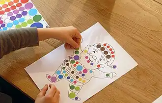 Travail de motricité fine consistant à coller les gommettes aux endroits prévus sur le dessin.