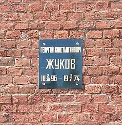 Photo en couleur d'une plaque fixée sur un mur de briques rouges.