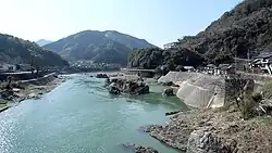 Photo couleur d'un couleur d'eau à l'eau bleu-vert avec un paysage de montagne en arrière-plan.