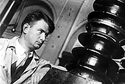 Photo en noir et blanc. Visage d'un homme s'appuyant sur un appareil.