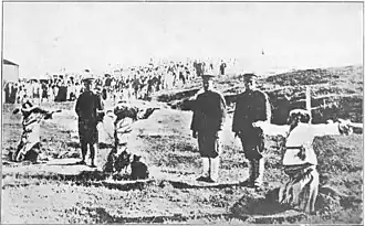 Photo de trois personnes en train d'être crucifiées. Elles sont à genou au sol, les bras fixés sur ces croix. Derrière elles, des hommes en uniforme procèdent à l'exécution.