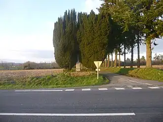 Photographie actuelle du lieu de la bataille. Il s'agit d'un carrefour de deux routes, une des deux est bordée d'arbres.