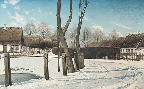 Une route enneigée près d'habitations.