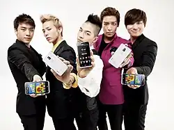 Photographie de cinq jeunes hommes en tenues à la mode, montrant chacun un smartphone