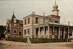 Carte postale colorée montrant un bâtiment d'inspiration mauresque, une femme se protégeant avec une ombrelle en premier plan.