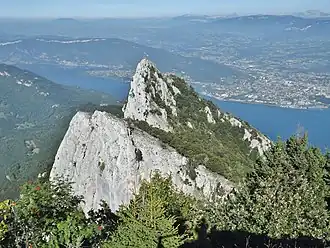 Vue de la dent du Chat depuis Molard Noir (1&nbsp;443&nbsp;m), à l'ouest, surplombant le lac du Bourget ; Aix-les-Bains est à l'arrière-plan le long de la rive est du lac.