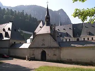 Porte d'entrée dans le mur d'enceinte donnant accès aux bâtiments aux toits gris d'un monastère.
