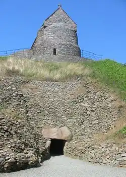 Entrée restaurée de la tombe néolithique de La Hougue Bie. La chapelle repose sur le monticule.