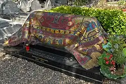 Tombe en forme de pavé, recouverte d’un tapis en mosaïque.