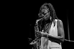 une Noire-Américaine avec des grosses lunettes joue du saxophone