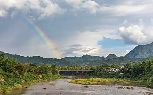Paysage avec arc-en-ciel et le Vieux Pont au-dessus de la rivière Nam Khan, rue Phetsarat, à Luang Prabang. Juin 2018.