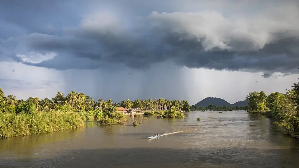 Paysage avec des nuages orageux et une pirogue sur le Mékong à l'heure dorée, depuis le pont entre Don Det et Don Khon, Si Phan Don.