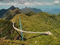 Pont suspendu au-dessus de petites collines typiques de l'Asie du Sud-Est.
