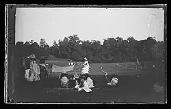 Photo noir et blanc d'un match de lawn tennis dans un parc.