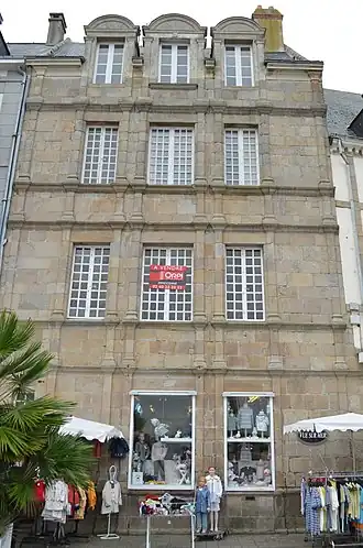 Vue d’une façade de maison en granit, à trois étages.