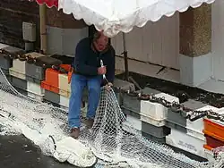 Un pêqueu (pêcheur) ravaudant ses filets près du funiculaire.
