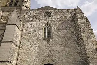 Vue de la façade laissant deviner l’ornementation du portail et les dix niches le surmontant, martelées lors des guerres de Religion